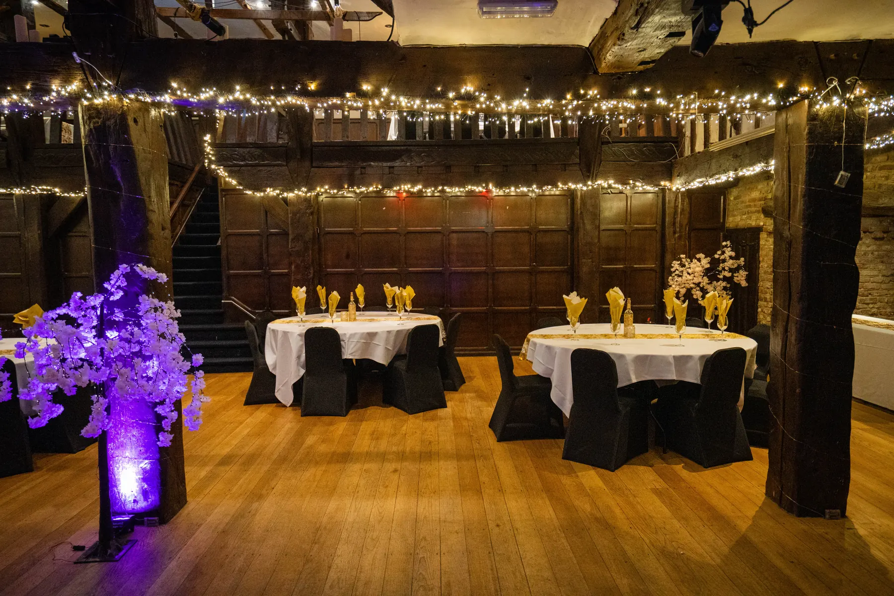 Purple-lit blossom trees beside tables in the Baronial Hall